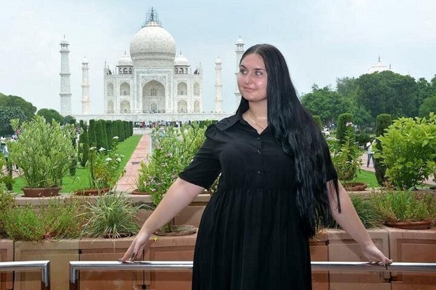 A person standing with arms outstretched in front of the Taj Mahal. 4