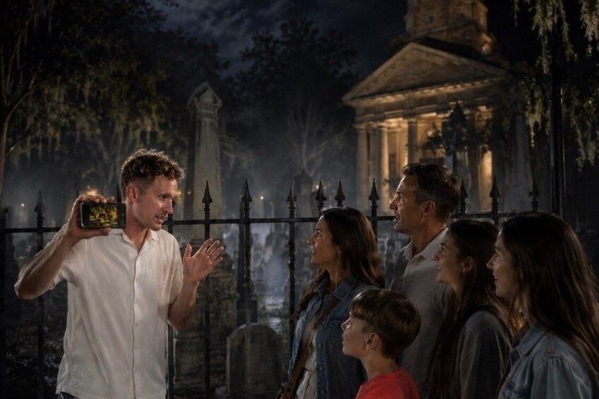 A group of people standing in front of a cemetery at night. 1