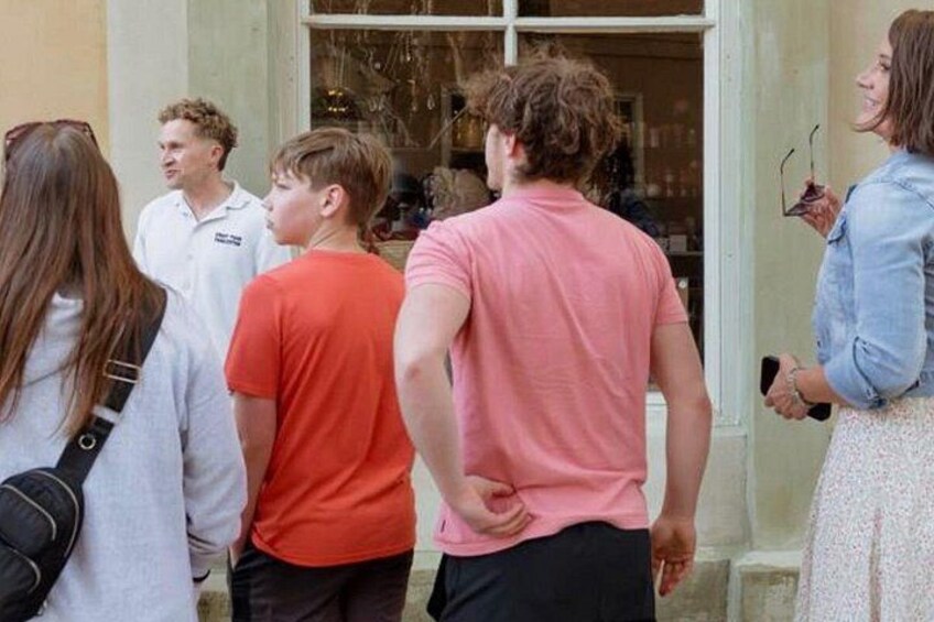 A group of people standing outside a building with a window. 5