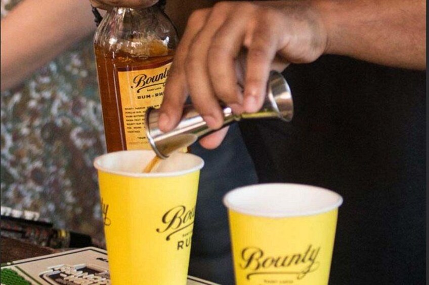 Una persona versa un drink da una bottiglia in un bicchiere di carta giallo con marchio 'Bounty'. 5