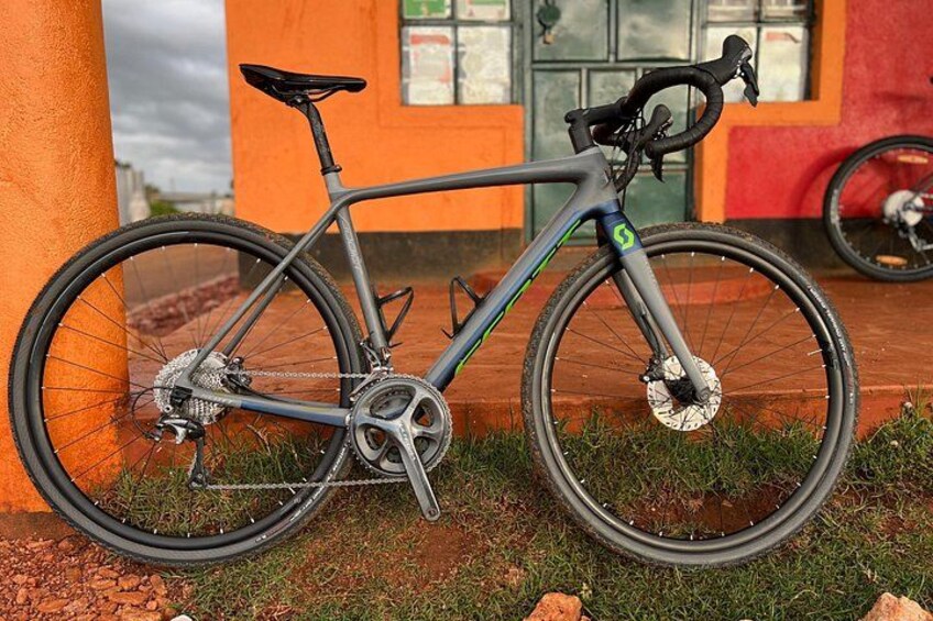 A grey bicycle with a green logo, parked against an orange wall. 3