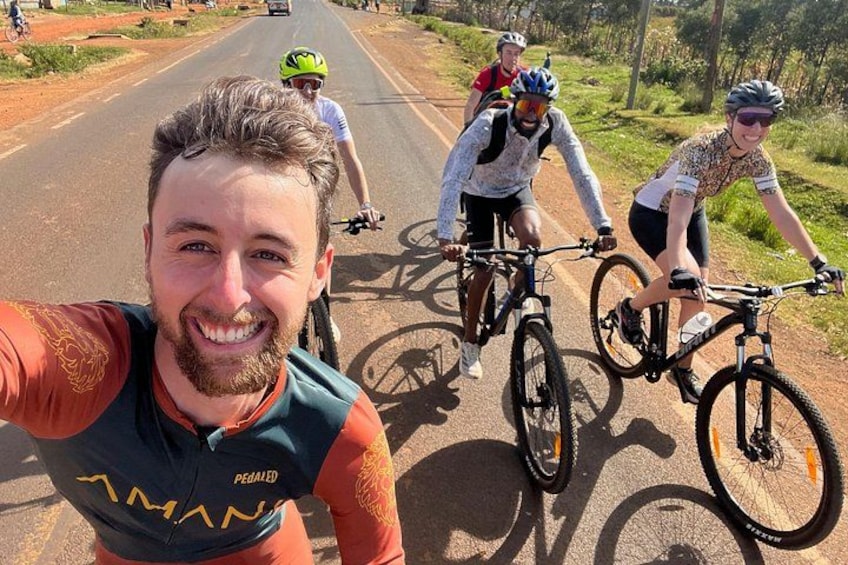 A group of cyclists on a paved road with greenery on the sides. 1