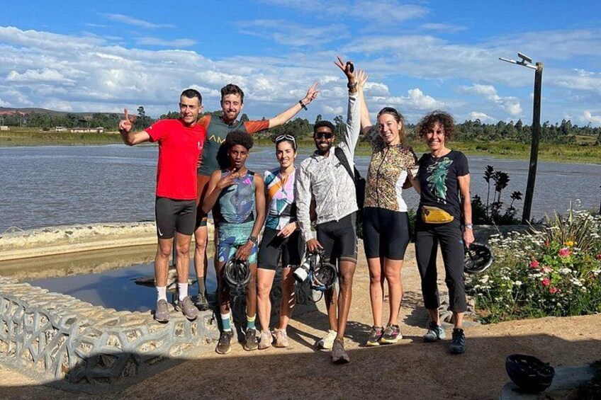 A group of people standing by a river, some holding bicycles. 4
