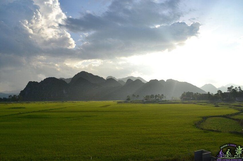 A green field with mountains in the background and a cloudy sky. 5