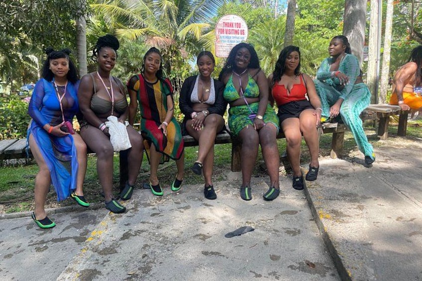 Un groupe de personnes est assis sur un banc dans un parc, à côté d’un panneau sur lequel on peut lire : « MERCI DE VOTRE VISITE ». 3