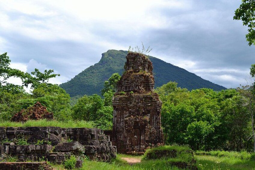 A ruined temple structure surrounded by lush greenery and a mountain in the background. 4