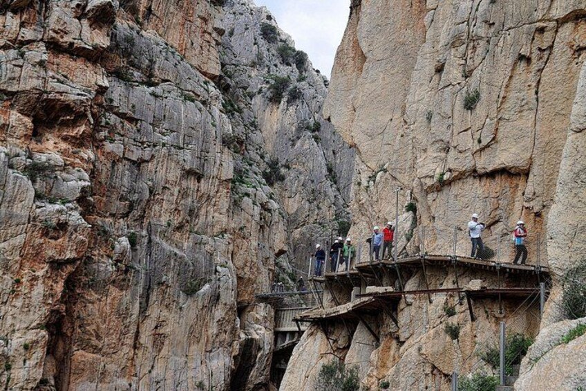 A rocky canyon with a wooden walkway and people standing on it. 2