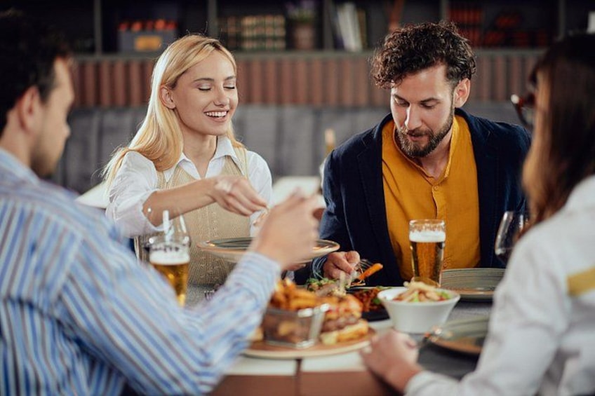 En gruppe mennesker spiser på en restaurant med mad og drikke på bordet. 2