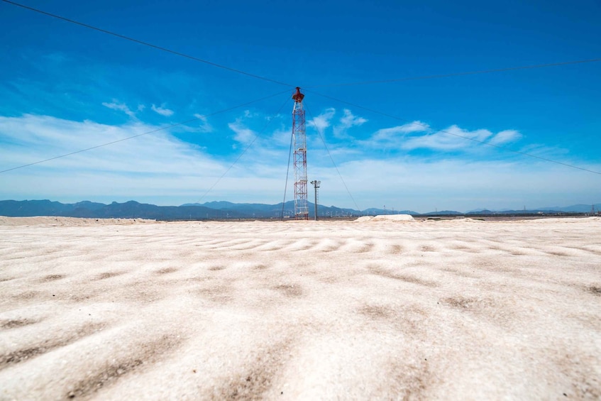 A tall communication tower in a desert landscape with mountains in the background. 4