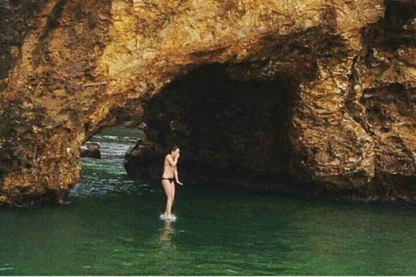 Una persona in acqua sotto un arco roccioso. 1