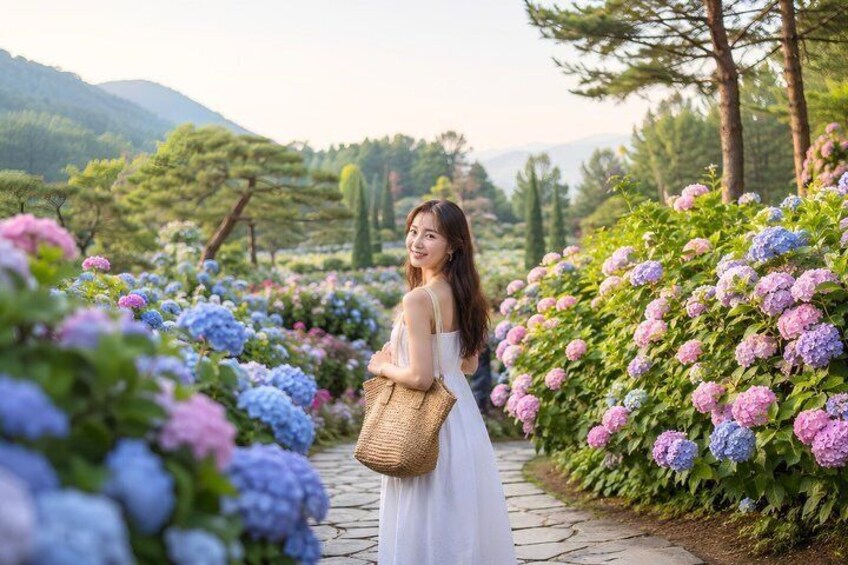 Una mujer con un vestido blanco caminando por un jardín con arbustos de hortensia. 1