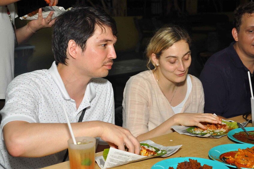 Three people dining at a restaurant with various dishes on plates. 4