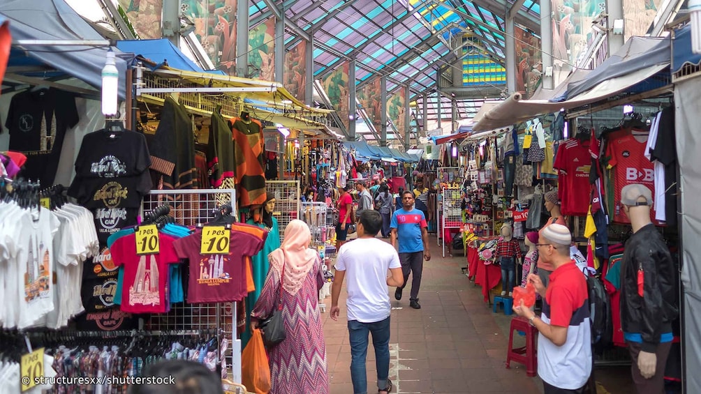 A bustling indoor market with various stalls selling clothes and accessories. 2