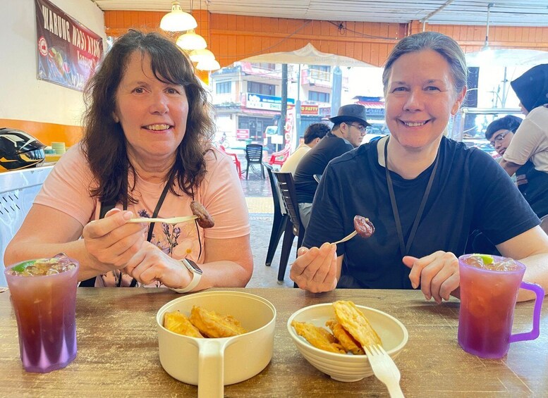 Two people sitting at a table with food and drinks. 5