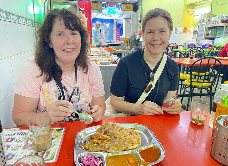 Two people sitting at a table with food and drinks. 2