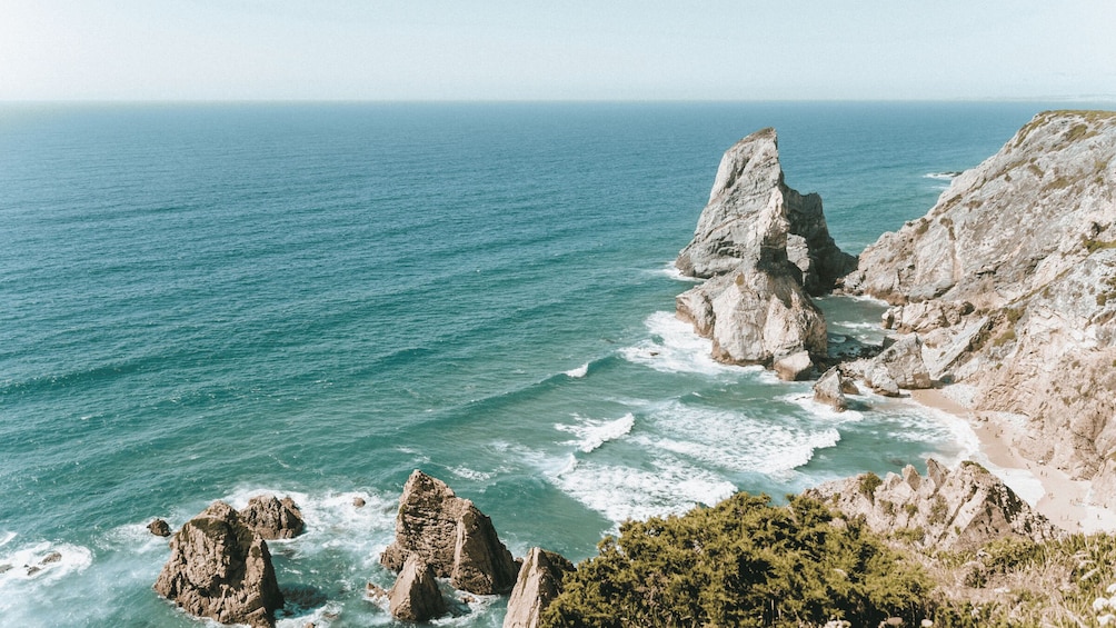 A coastal landscape with rocky formations and a beach. 4