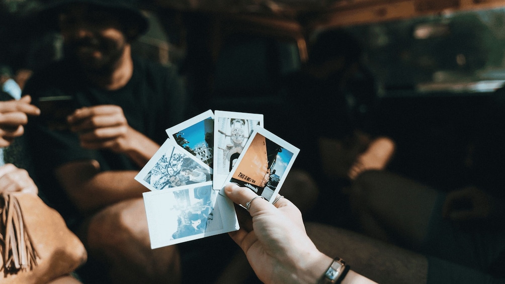 A person holding several photographs. 3
