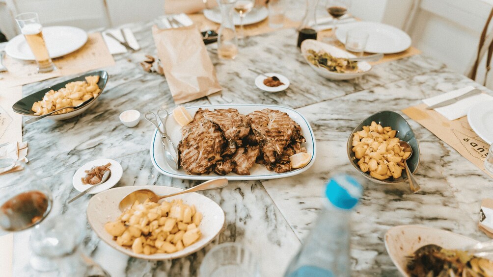 Et marmorbord med forskellige retter, herunder stegt kød, kartofler og et glas øl. 4
