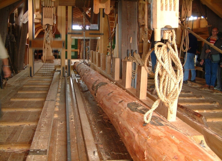 A wooden log being processed in a mill with machinery and ropes. 2