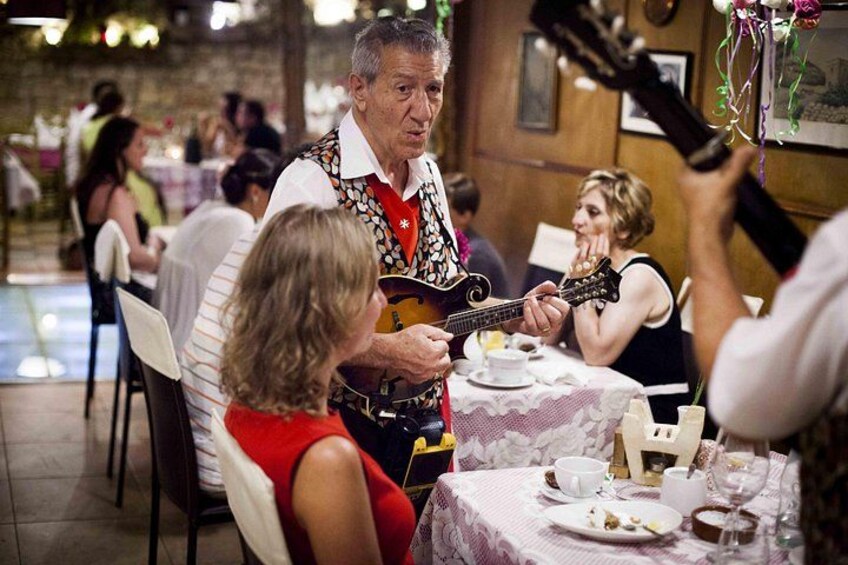 A man playing guitar at a restaurant table. 1