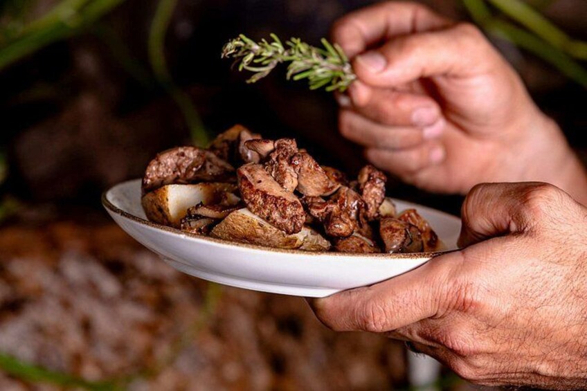 A person holding a plate of cooked meat and potatoes. 5