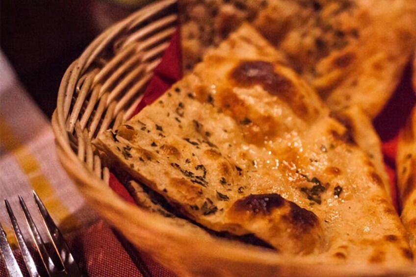 A basket of naan bread with visible herbs. 3