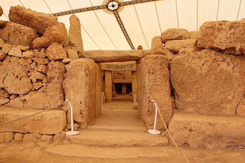 An ancient stone structure with large, upright stones and a central passageway. 2
