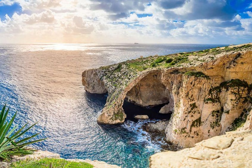 Paisaje costero con una formación rocosa destacada, que presenta un arco natural y una vista despejada del océano. 3