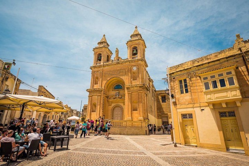 Una iglesia histórica con dos torres, una calle adoquinada y gente caminando. 5