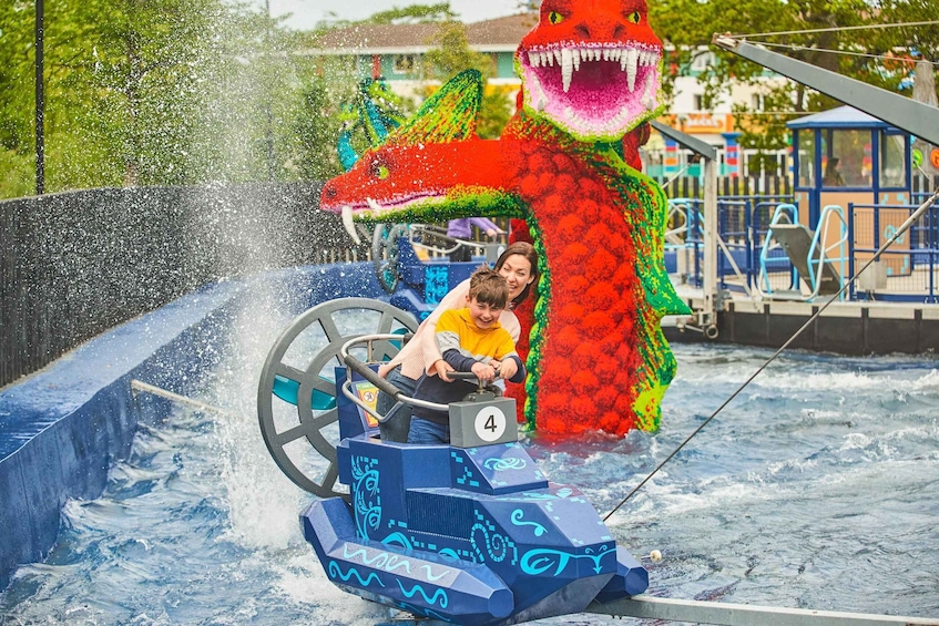 A water ride with a dragon-themed vehicle and a large dragon statue in the background. 4