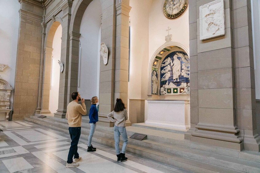 Et interiør med klassisk arkitektur, herunder søjler og et detaljeret muralmaleri. 2