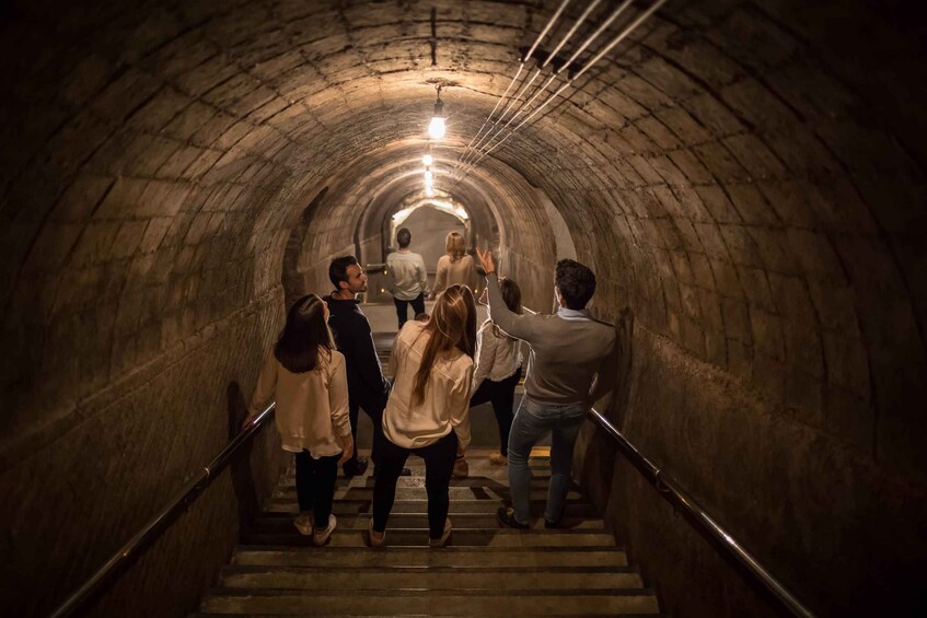 A group of people ascending a stone staircase in a tunnel. 4