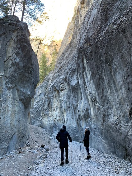 A narrow canyon with rocky terrain and a person hiking with a child. 1