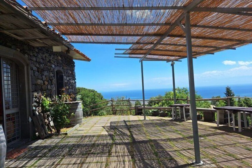 Una casa in pietra con una terrazza in legno, un pergolato e vista sull'oceano. 4