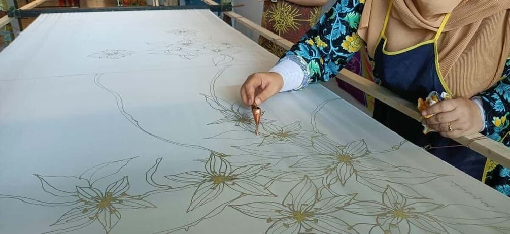 A person drawing floral patterns on a large fabric. 5