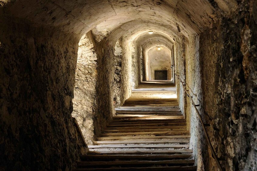 A stone staircase in a tunnel with arched ceilings. 4