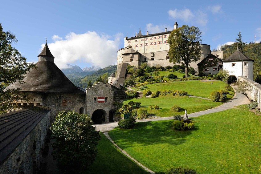 A castle on a hill with a well-maintained garden and a small tower. 1