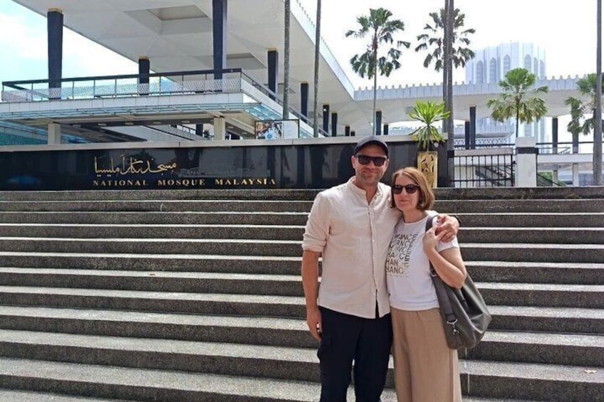 A man and a woman standing in front of the National Mosque Malaysia. 2