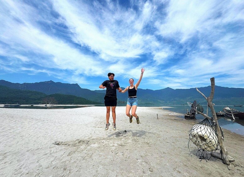Two people jumping on a beach with mountains in the background. 3