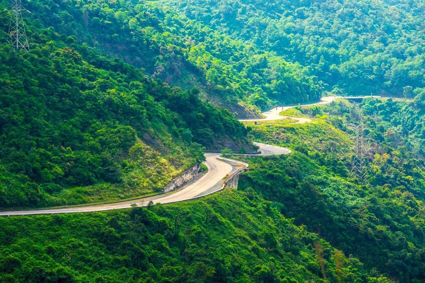 A winding mountain road surrounded by dense green forest. 1