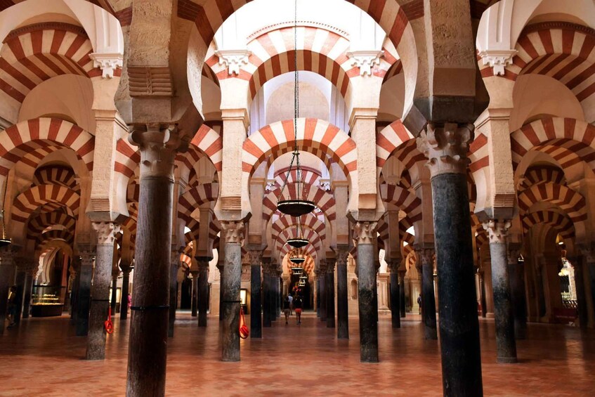 A grand hall with high arches and columns, featuring a distinctive red and white striped pattern on the arches. 4