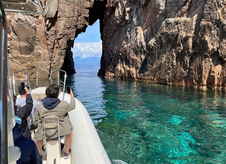 A boat passing through a rocky arch in clear blue water. 1