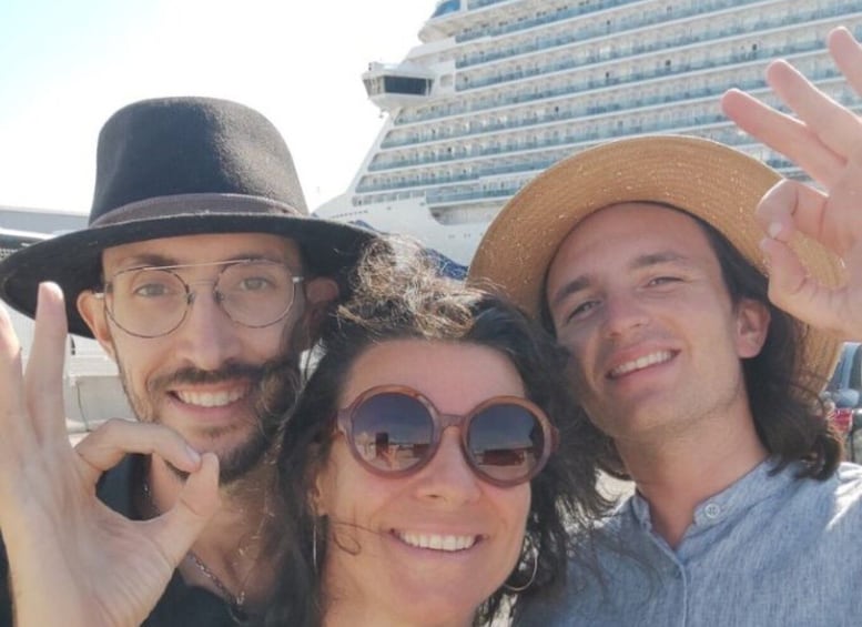 Trois personnes posent devant un grand navire de croisière. 2