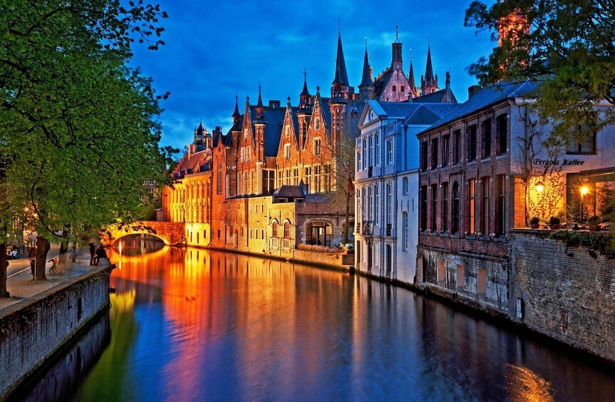 Un canal con edificios reflejados en el agua, un puente y un edificio con el rótulo 'Pergok Kaffe'. 1