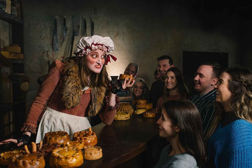 A person serving food to a group of people in a rustic setting. 2