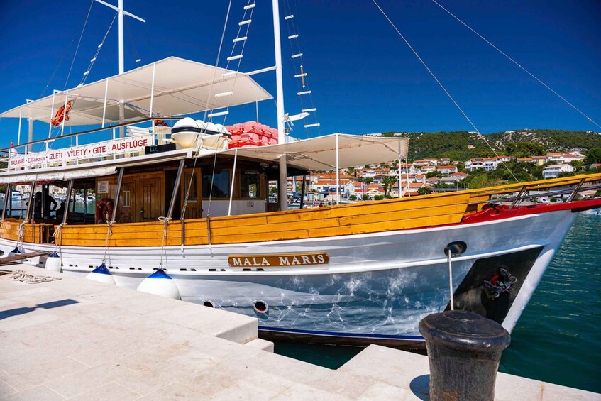 A boat named 'MALA MARIS' docked at a pier with a coastal town in the background. 3