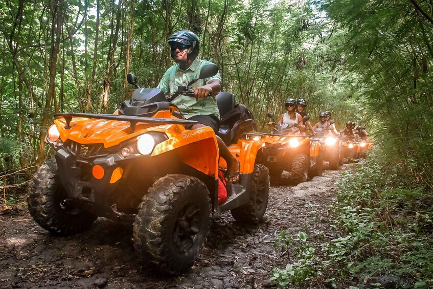 Un groupe de véhicules tout-terrain orange circule dans une zone boisée. 3