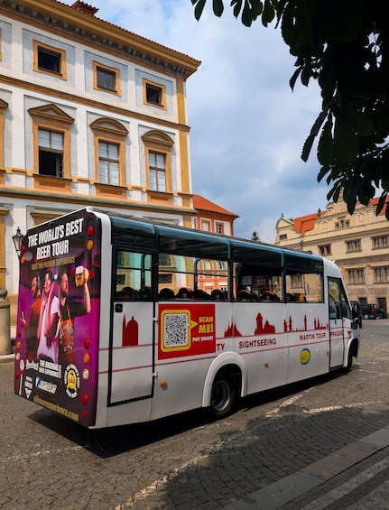 A tour bus with a beer tour advertisement parked on a cobblestone street. 3