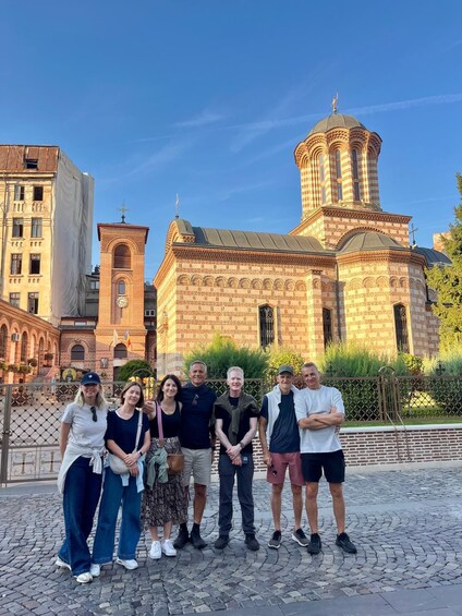 A group of people standing in front of a historic church with a tall bell tower. 5