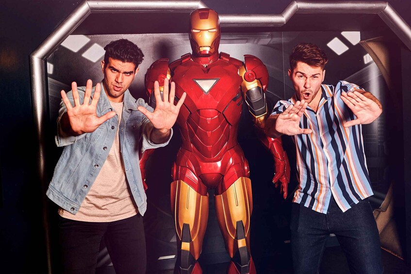 Three people in front of a large Iron Man suit. 2